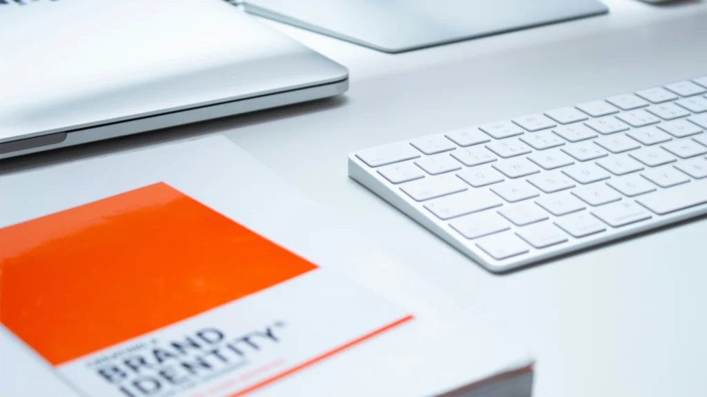 Desk with Mac, keyboard and a brand identity book