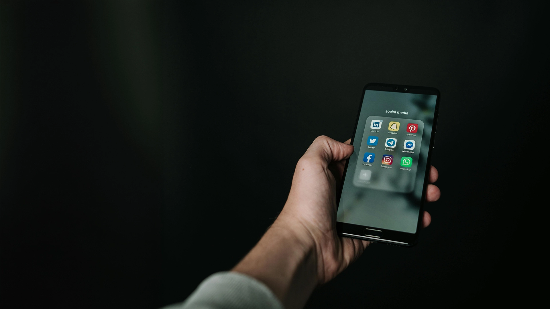 Man holding a mobile phone displaying social media apps