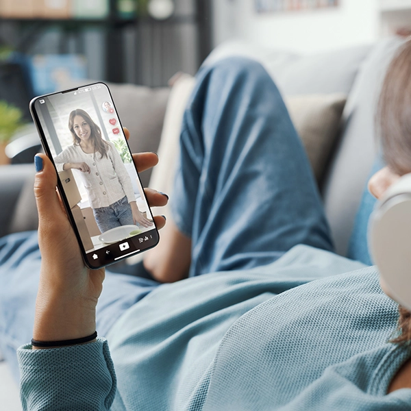 Lady lying on a couch watching social media reels on her phone