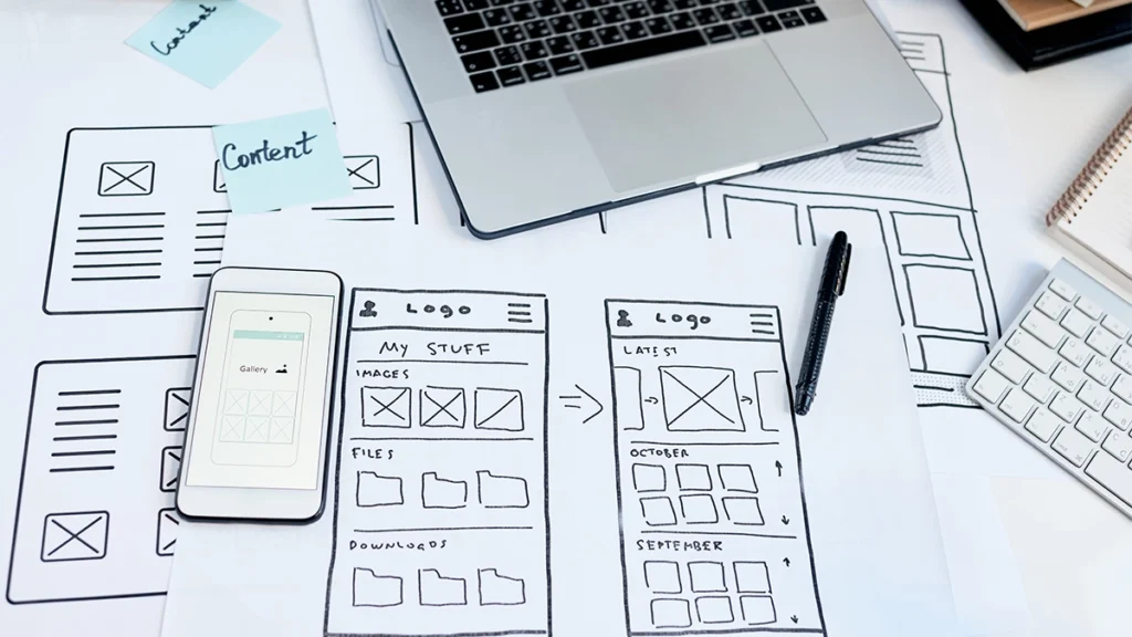 Close-up of workplace of user interface designer creating usable application for devices, sketches and smartphone on table