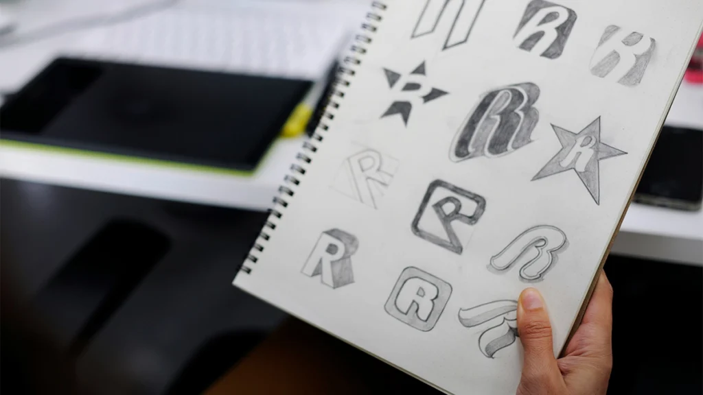 Person holding a sketch book with hand drawn logo designs