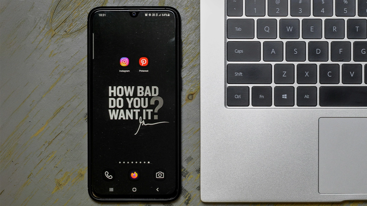Phone with social media icons next to a laptop.