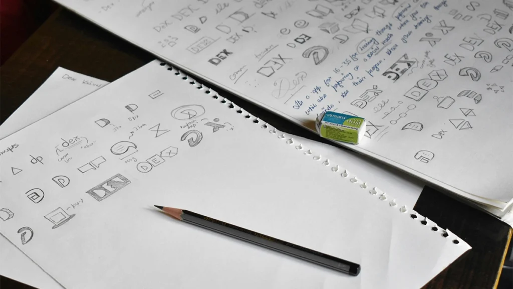 a pencil sitting on top of a pile of paper with logo designs