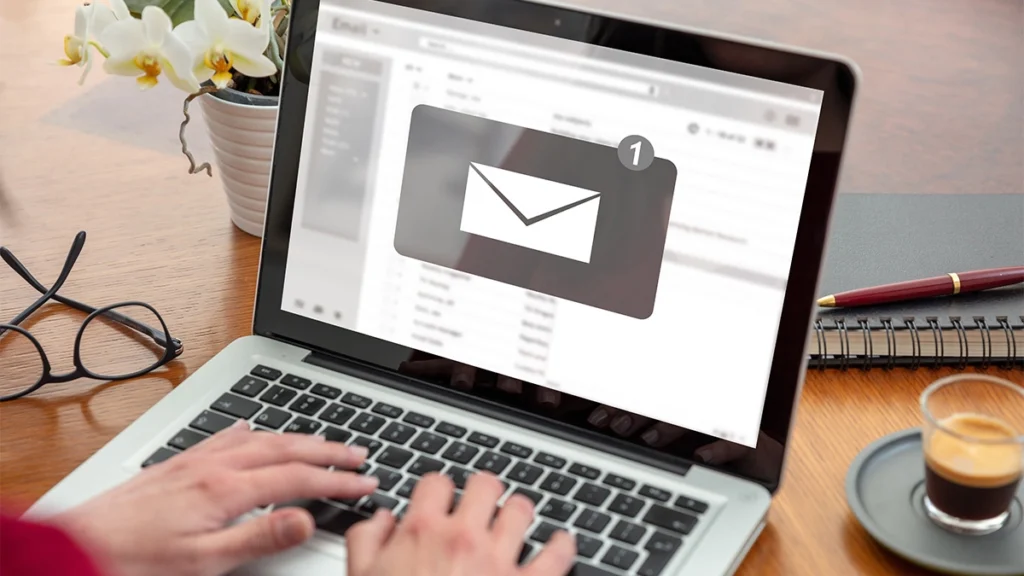 Email notification concept, woman working with a computer laptop, one new inbox e mail message on the screen, business office desk background