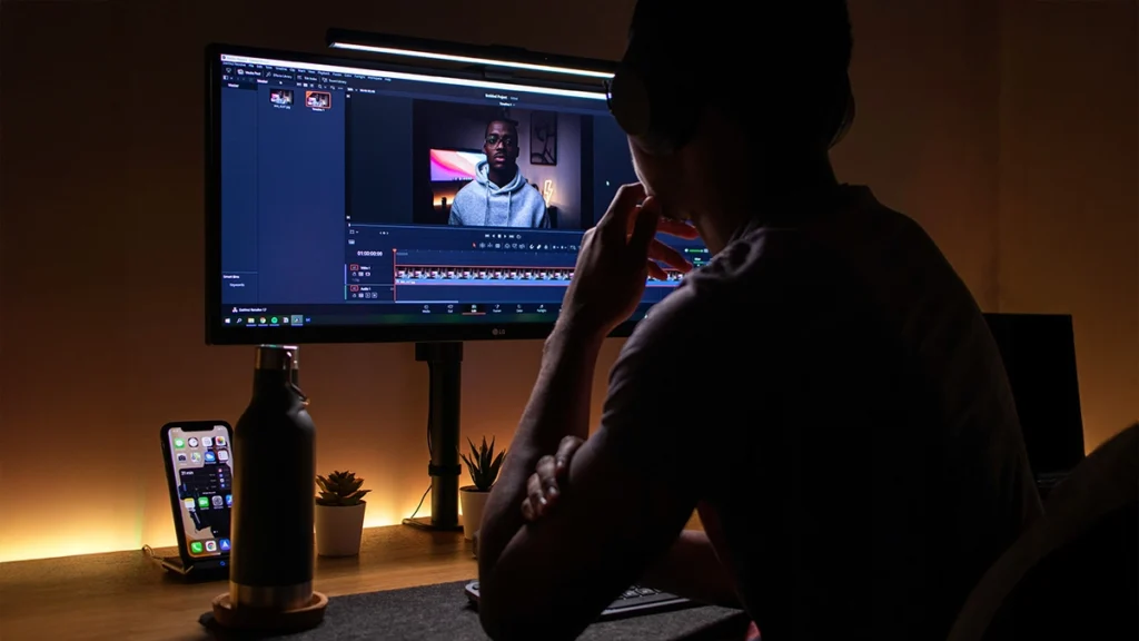 Man sitting at a desk editing a video on computer