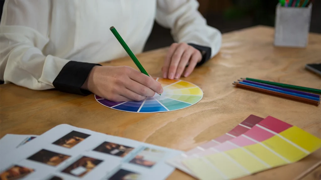 Close-up of a female graphic designer working at desk with colour wheel