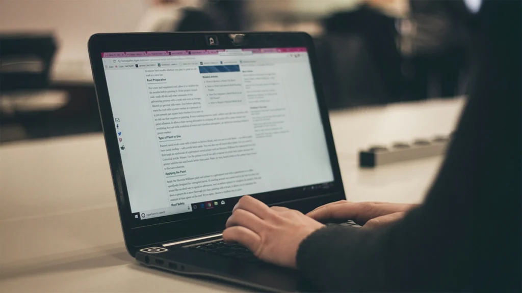 Person writing a blog post on a laptop