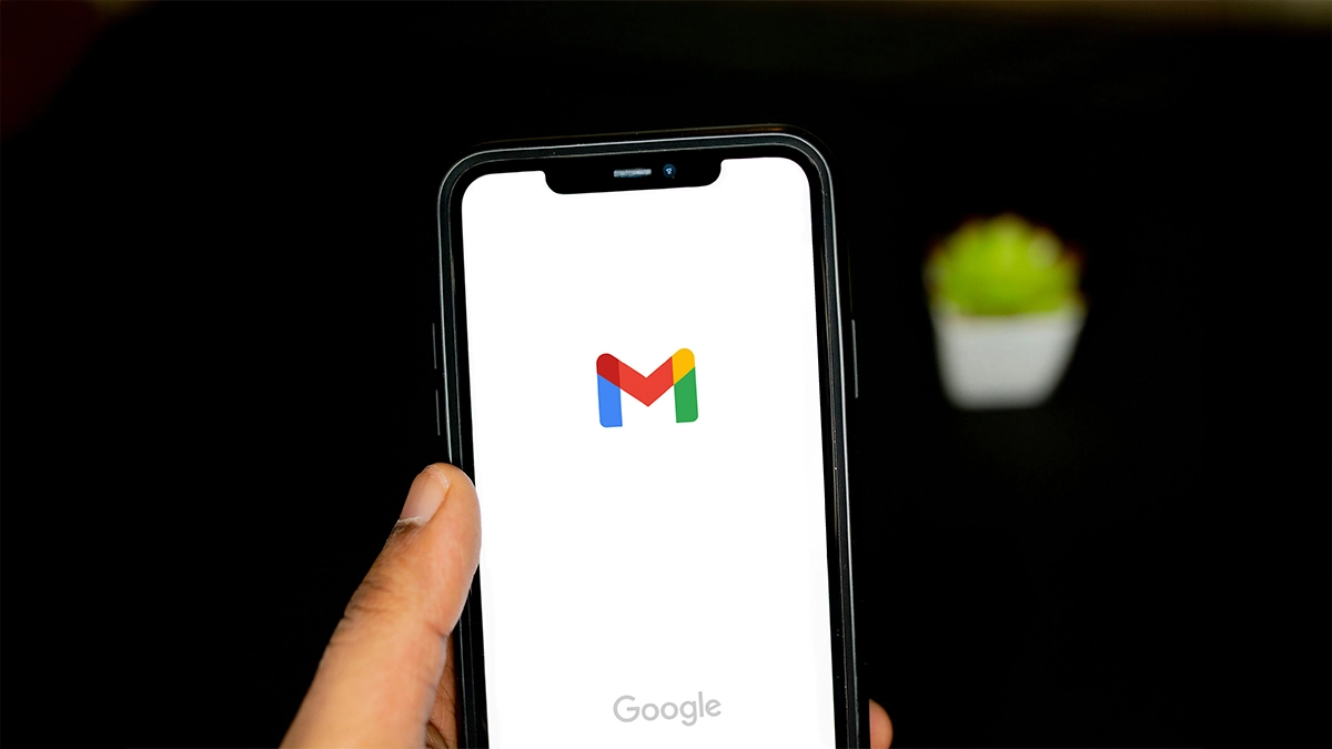 Hand holding mobile phone with Gmail logo