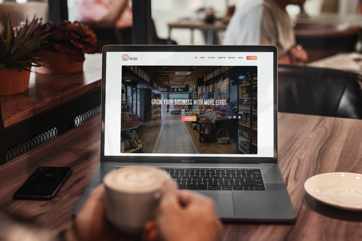 Man sitting in coffee shop, holding a cup of coffee, looking at the Market to Shelf Masters website