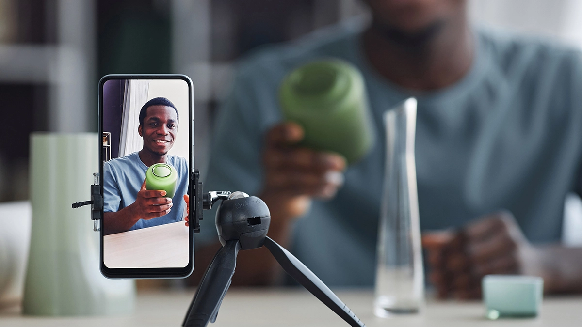 Happy young craftsman with handmade vase on screen
