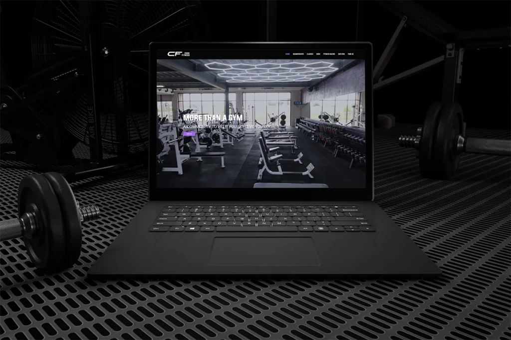 Laptop sitting on gym floor with a mockup of Code Fitness website
