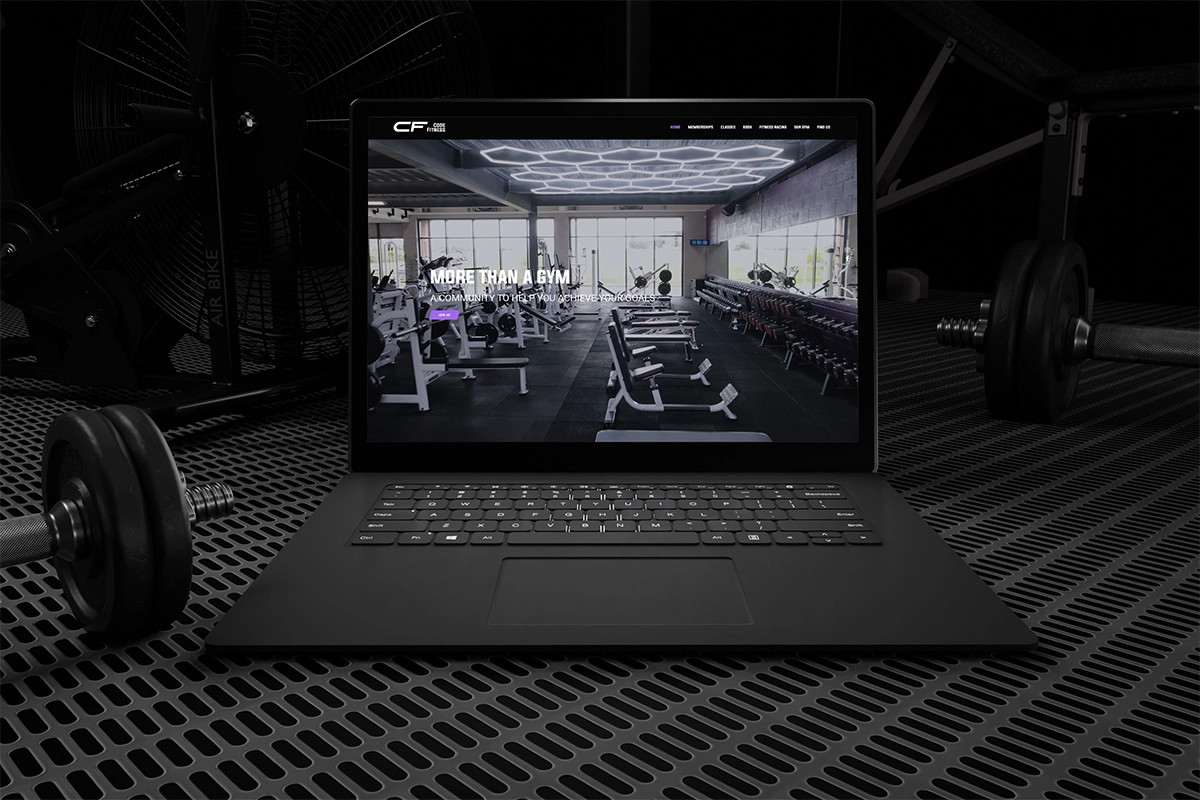 Laptop sitting on gym floor with a mockup of Code Fitness website