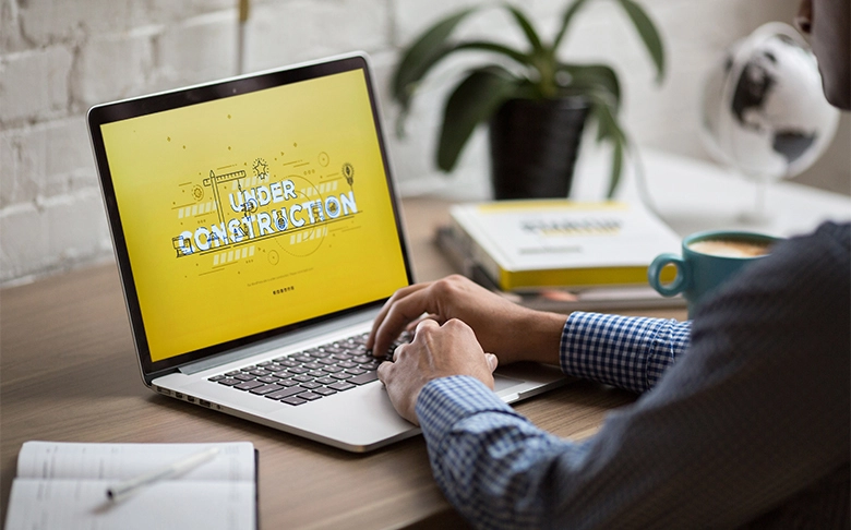 Man using a laptop with a website under construction