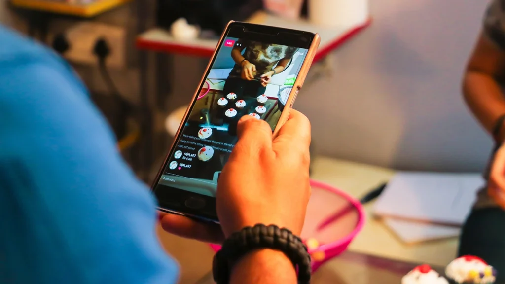 Person on phone streaming cupcake decorating