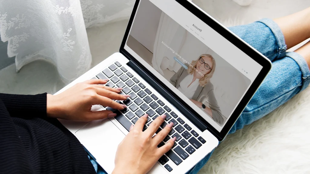 Woman sitting on floor looking at Account8 website on laptop