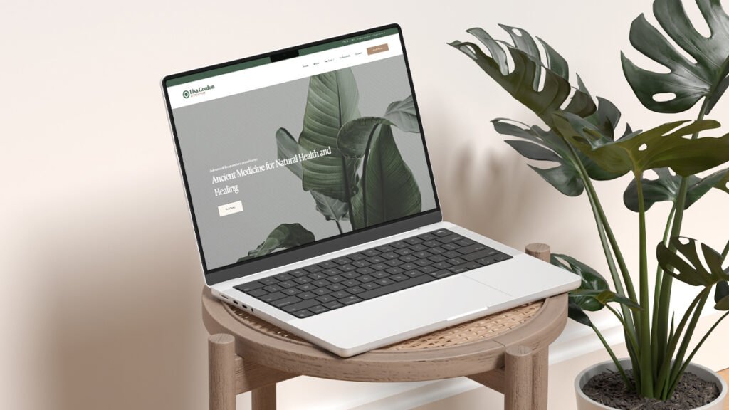 Laptop sitting on a wicker chair with the Lisa Gordon Acupuncture website, and plant in the background