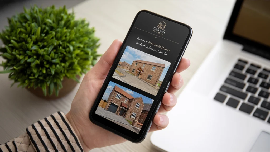 Person holding a phone with the Oakwell Homes website