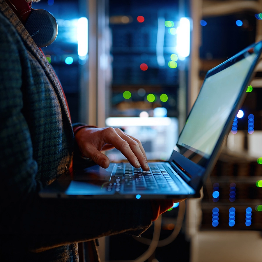 Technician using laptop in dark server room