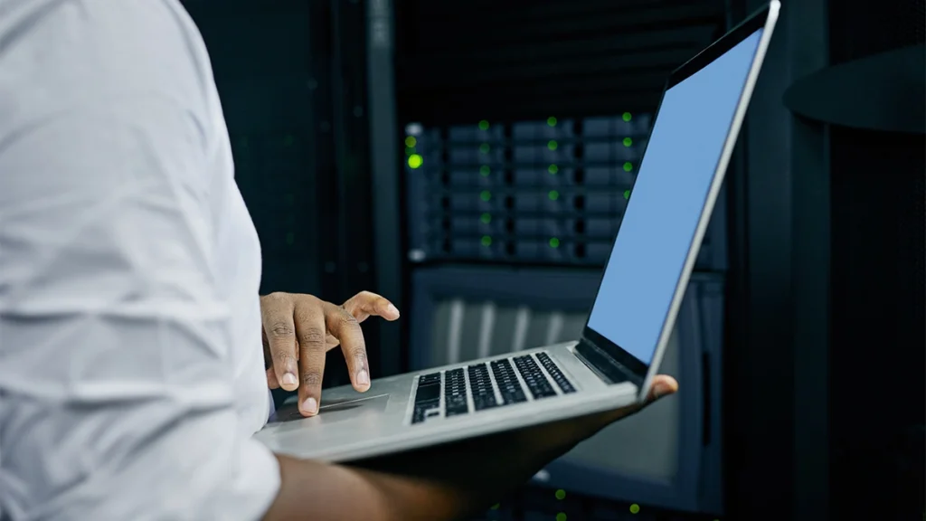 Man working on a laptop in front of a website hosting server