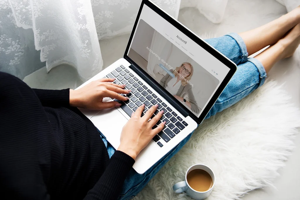 Woman sitting on floor looking at Account8 website on laptop