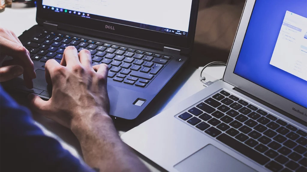 Man working on two computers side by side migrating wordpress website