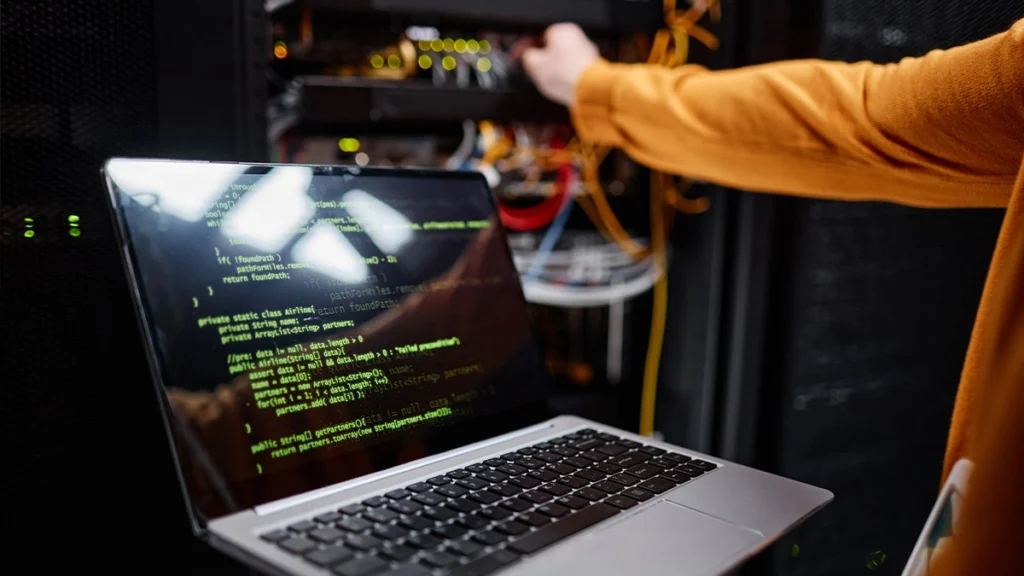 Person with laptop plugging in a cable to a server